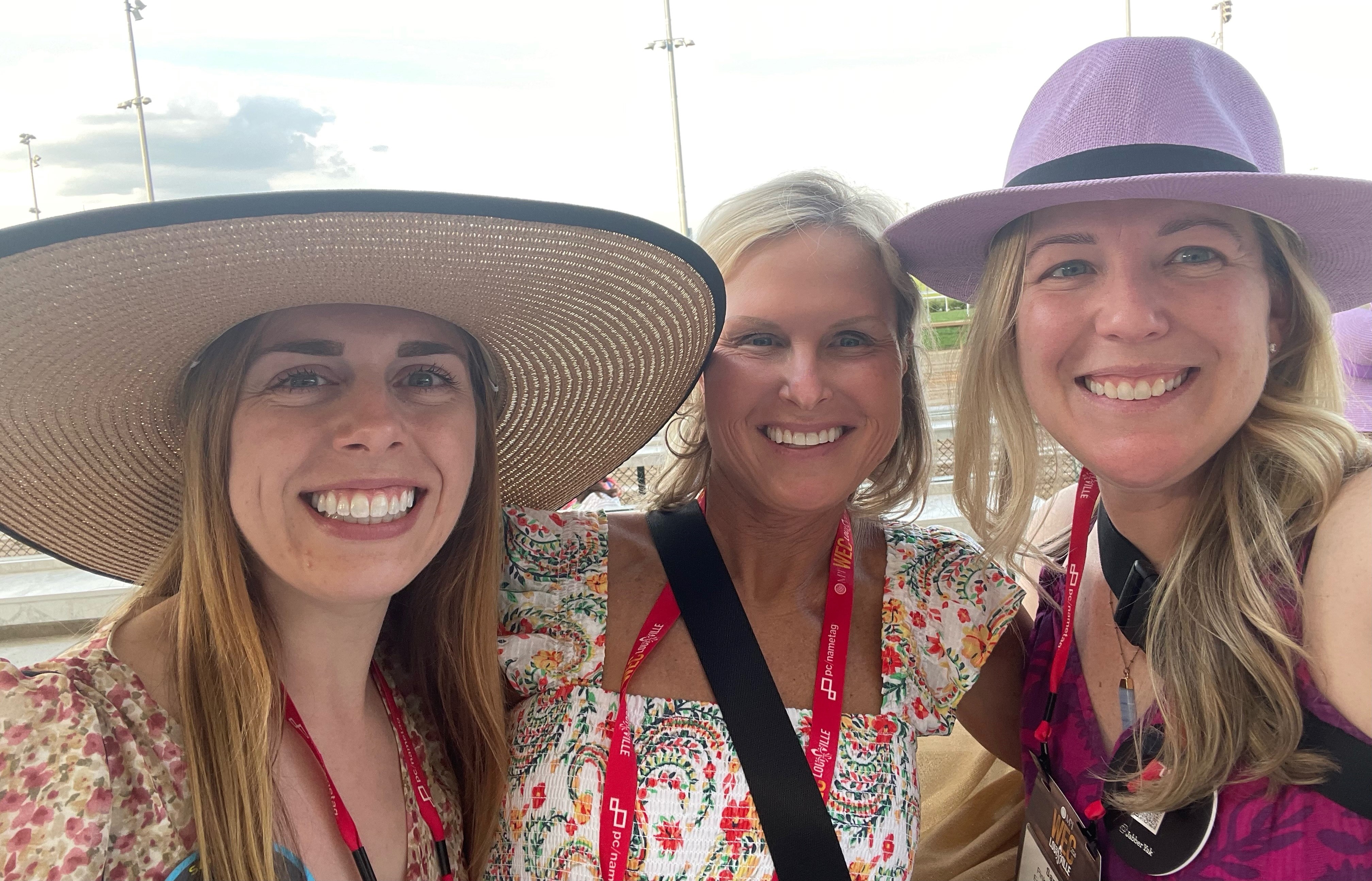 Three women wearing big hats