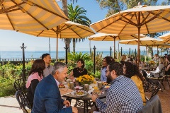 Group of people eat at tables near the ocean
